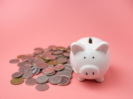 White piggy bank With a pile of coins On a pink background. saving money concept.