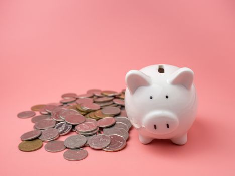 White piggy bank With a pile of coins On a pink background. saving money concept.