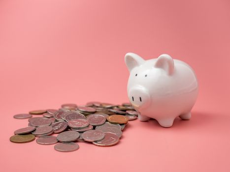 White piggy bank With a pile of coins On a pink background. saving money concept.