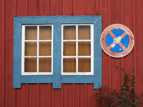 Red limber wall with blue white window and traffic sign.