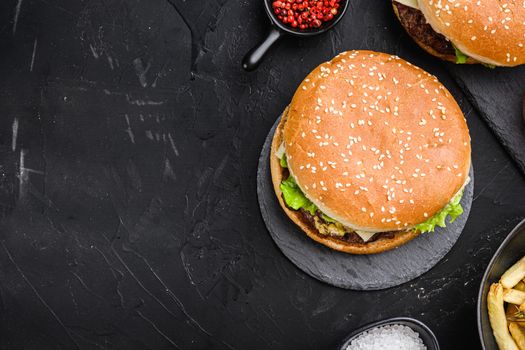 Angus burger with cheese, lettuce, and tomato on black background, flat lay with copy space.