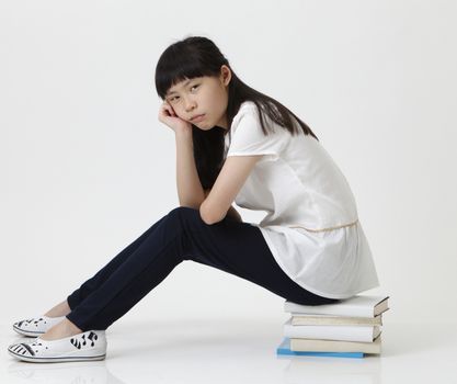 chinese girl sat on  books looking at camera