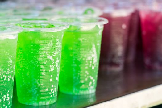 Multicolored drinks in clear plastic glasses