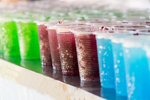 Multicolored drinks in clear plastic glasses