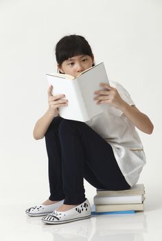 chinese girl sitting on stack of book reading
