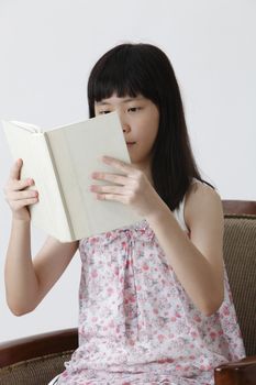 chinese girl sitting on the sofa reading book 