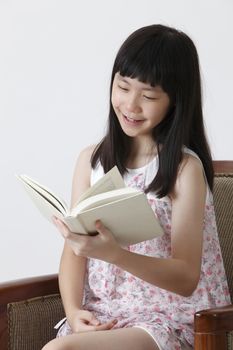 chinese girl sitting on the sofa reading book with smile