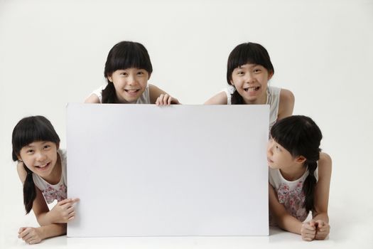 few girl with same look pointing at blank cardboard
