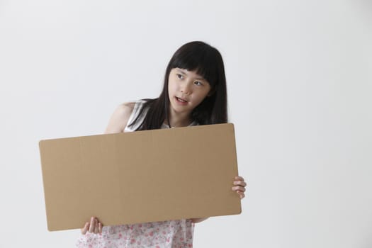 chinese girl holding a brown message board looking away