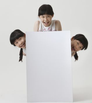 few girl with same look hiding blank cardboard