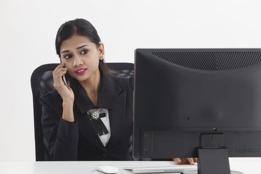 woman sitting in front of the monitor talking on the phone