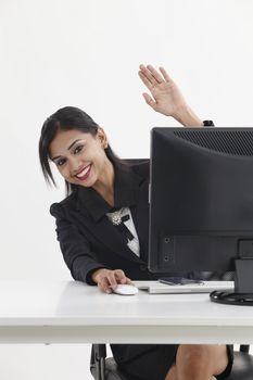 business woman sitting in front of computer,talking and waving to camera