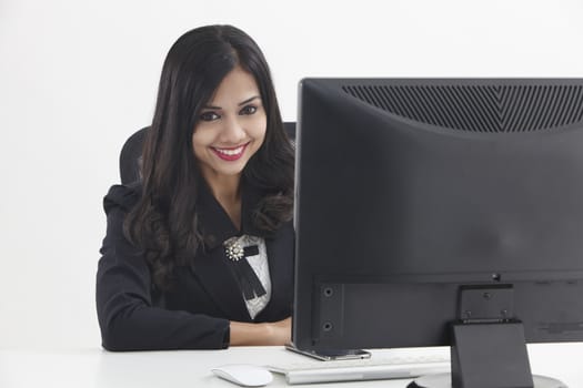 business woman sitting in front monitor looking at camera