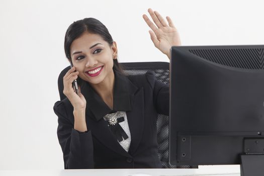 business woman sitting in front of computer,talking and waving to camera