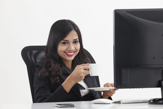 business woman sitting in front monitor having tea break
