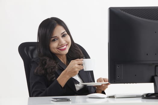 business woman sitting in front monitor having tea break