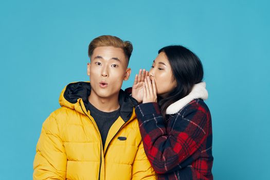 Man and woman in winter jackets communicating fashionable clothes family studio blue background