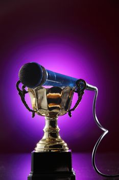 golden trophy  and microphone with purple background