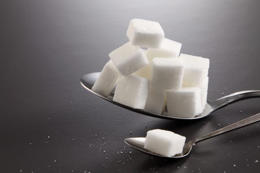 big or super size spoon with pile of cube white sugar