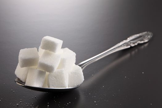 big or super size spoon with pile of cube white sugar