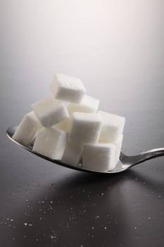 big or super size spoon with pile of cube white sugar