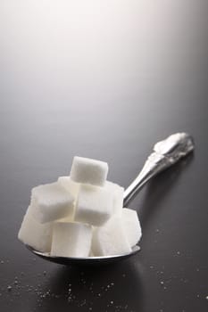 big or super size spoon with pile of cube white sugar