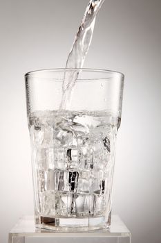 Pouring water to the glass isolated on white background