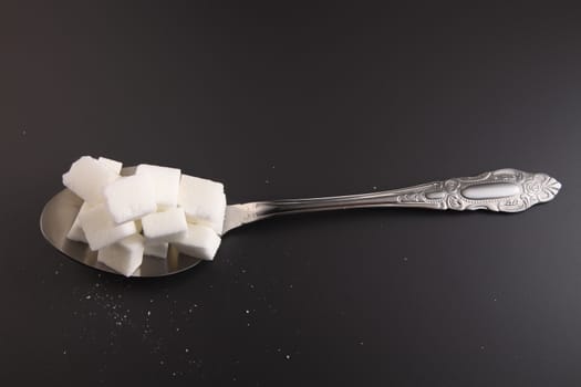 big or super size spoon with pile of cube white sugar