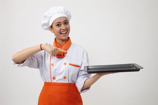 Portrait of a Indian woman with chef uniform holding an empty tray