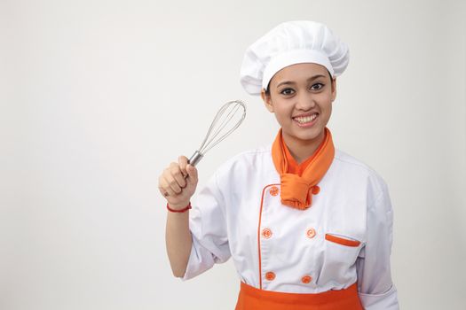 Portrait of a Indian woman with chef uniform holding whisk