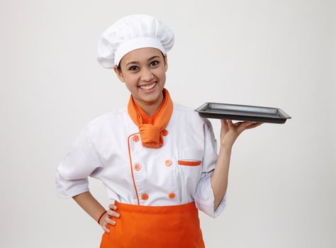 Portrait of a Indian woman with chef uniform holding an empty tray