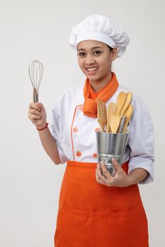 Portrait of a Indian woman with chef uniform holding whisk and spatula