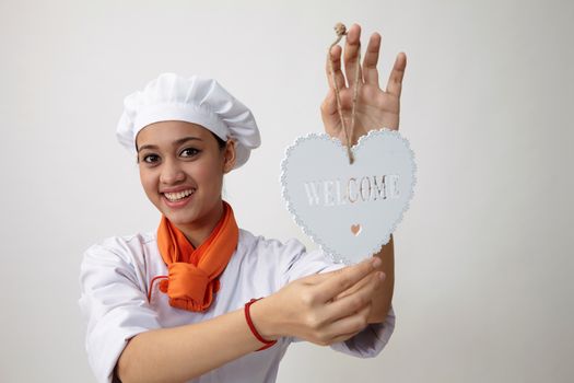 Indian woman with chef uniform holding a welcome signage