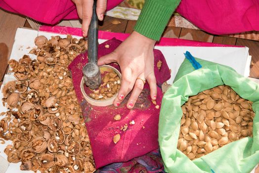 Elevated close-up view of a young woman cracking walnuts at home with a hammer.
