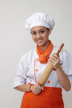 Portrait of a Indian woman with chef uniform holding rolling pin