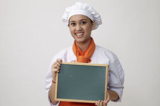 Portrait of a Indian woman with chef uniform holding chalk board