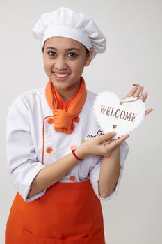 Indian woman with chef uniform holding a welcome signage