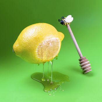 Honey trickles and drips from levitating lemon. Lemon and dipper for honey on green background. Unreal objects. Art fantasy. Minimal style