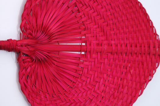 Red color native fan made from palm leaves on white background