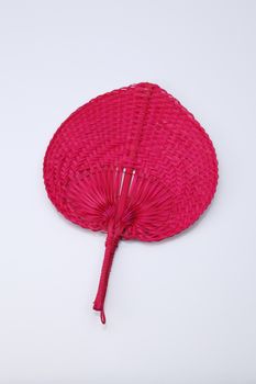 Red color native fan made from palm leaves on white background