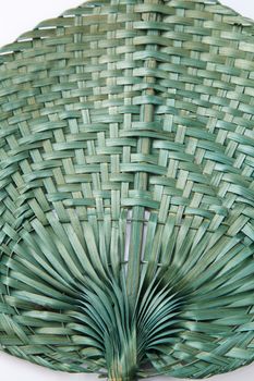 Green color native fan made from palm leaves on white background