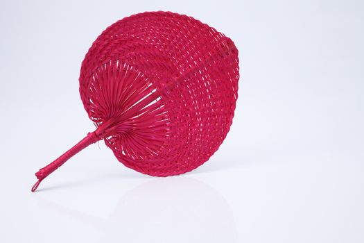 Pink color native fan made from palm leaves on white background