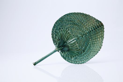 Green color native fan made from palm leaves on white background