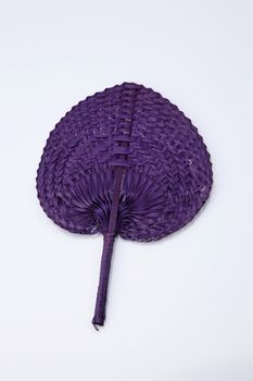 Purple color native fan made from palm leaves on white background