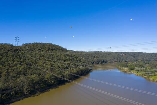 An electricity transmission tower and cables across a river in regional New South Wales in Australia