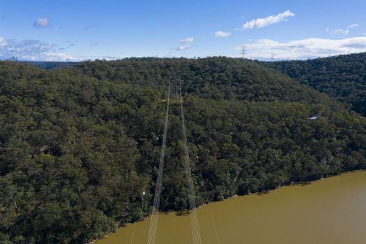 An electricity transmission tower and cables across a river in regional New South Wales in Australia