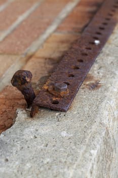 An old rusty bolt and metal angle iron section on broken concrete