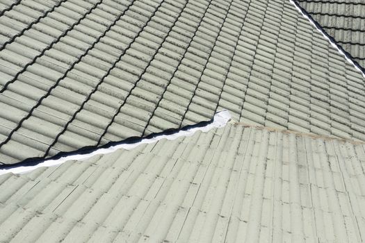 Close up of green tiles on a  roof in the sunshine.