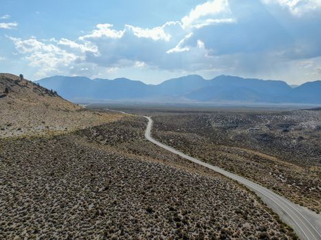 Aerial view of asphalt road in the middle of dusty dry desert land in Lee Vining, Mono County, California, USA