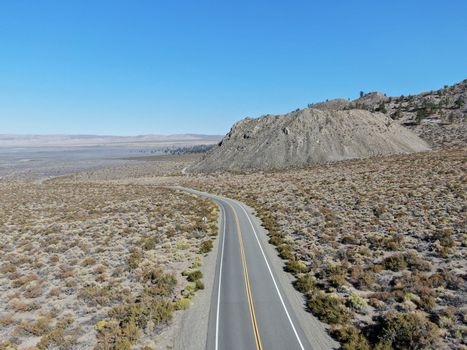 Aerial view of asphalt road in the middle of dusty dry desert land in Lee Vining, Mono County, California, USA